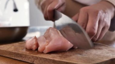 Mutfakta yemek pişirmek. Asyalı Müslüman kadın tavuk göğsü eti kesiyor. Yemek hazırlığı
