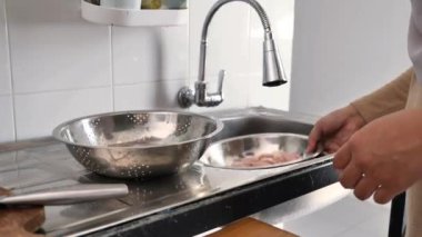 Mutfakta yemek pişirmek. Asyalı Müslüman kadın kestikten sonra tavuk etini yıkayıp temizliyor. Yemek hazırlığı