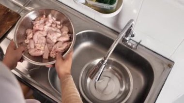 Mutfakta yemek pişirmek. Asyalı Müslüman kadın kestikten sonra tavuk etini yıkayıp temizliyor. Yemek hazırlığı
