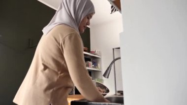 Mutfakta yemek pişirmek. Asyalı Müslüman kadın kestikten sonra tavuk etini yıkayıp temizliyor. Yemek hazırlığı