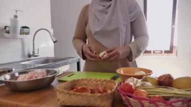 Mutfakta yemek pişirmek. Asyalı Müslüman kadın soğan ve sarımsak soyup doğruyor. Tavuk eti için salamura hazırlanıyor.