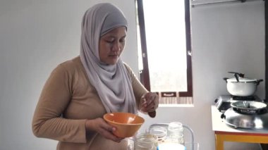 Mutfakta yemek pişirmek. Asyalı Müslüman kadın baharat ve otları karıştırıyor.
