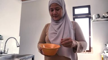 Mutfakta yemek pişirmek. Asyalı Müslüman kadın baharat ve otları karıştırıyor.