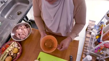 Mutfakta yemek pişirmek. Asyalı Müslüman kadın baharat ve otları karıştırıyor.