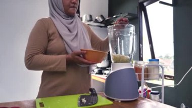 Mutfakta yemek pişirmek. Asyalı Müslüman kadın otlarla baharatları karıştırıyor.