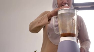 Mutfakta yemek pişirmek. Asyalı Müslüman kadın otlarla baharatları karıştırıyor.