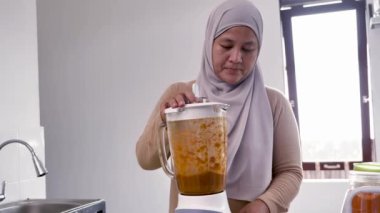 Mutfakta yemek pişirmek. Asyalı Müslüman kadın otlarla baharatları karıştırıyor.
