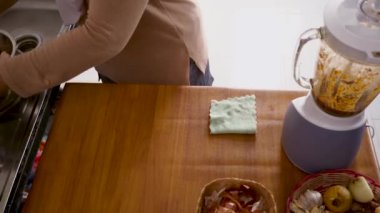Mutfakta yemek pişirmek. Asyalı Müslüman kadın blenderdan baharat ve otları kasedeki tavuk etinin üzerine döküyor, terbiye süreci