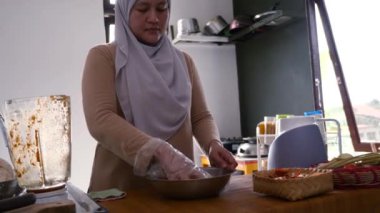 Mutfakta yemek pişirmek. Metal kasede tavuk etini terbiye eden birinin elini kapat.