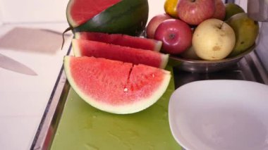 Asyalı Müslüman kadın mutfakta karpuz dilimliyor, yemek hazırlıyor.