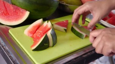 Asyalı Müslüman kadın mutfakta karpuz dilimliyor, yemek hazırlıyor.