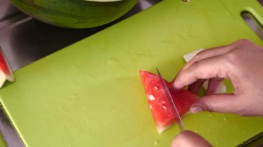 Asyalı Müslüman kadın mutfakta karpuz dilimliyor, yemek hazırlıyor.