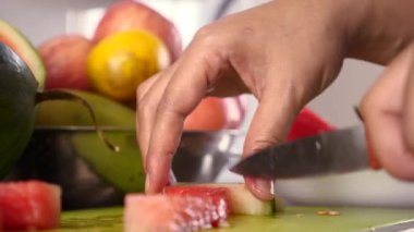 Asyalı Müslüman kadın mutfakta karpuz dilimliyor, yemek hazırlıyor.