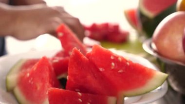 Asyalı Müslüman kadın mutfakta karpuz dilimliyor, yemek hazırlıyor.