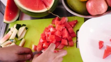 Asyalı Müslüman kadın mutfakta karpuz dilimliyor, yemek hazırlıyor.