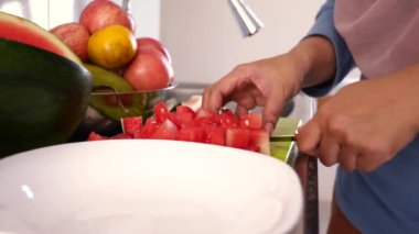 Asyalı Müslüman kadın mutfakta karpuz dilimliyor, yemek hazırlıyor.