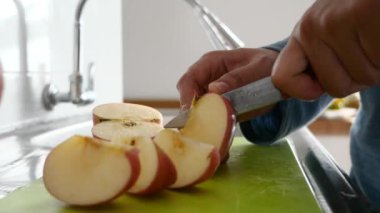 Asyalı Müslüman kadın mutfakta elma ve armut dilimliyor, yemek hazırlıyor.