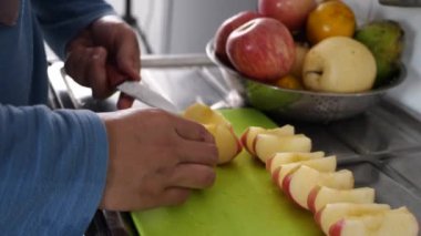 Asyalı Müslüman kadın mutfakta elma ve armut dilimliyor, yemek hazırlıyor.
