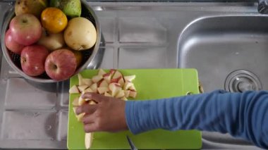 Asyalı Müslüman kadın mutfakta elma ve armut dilimliyor, yemek hazırlıyor.