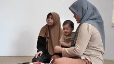 Asyalı Müslüman anne bebeğini taze meyvelerle, çocuklar için sağlıklı yiyeceklerle besler.