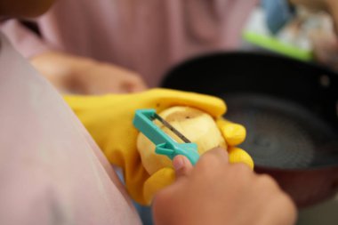 Anne ve küçük kız mutfakta yemek pişiriyor, yemek hazırlıyor, tavuk eti ve patates dilimliyor.