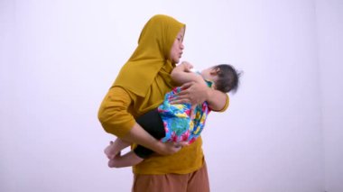 Asyalı Müslüman anne bebeğini mama şişesiyle besler.