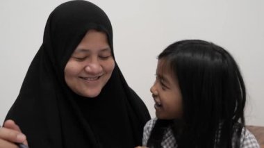 Asyalı Müslüman anne kızıyla oynayıp resim yapmayı öğreniyor, evde ebeveyn eğitimi dersi veriyor.