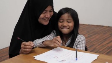 Asyalı Müslüman anne kızıyla oynayıp resim yapmayı öğreniyor, evde ebeveyn eğitimi dersi veriyor.