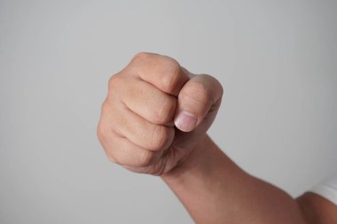 Erkek yumruğu. Gri arka planda yumruk atıyor.