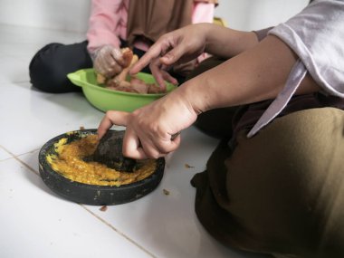 Endonezyalı Müslüman kadın kızıyla mutfakta yemek hazırlıyor, geleneksel otantik Asya yemekleri pişiriyor, doğal ışık.