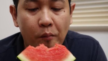 Karpuz meyvesi yiyen Asyalı adama yakın çekim, sağlıklı atıştırmalık.