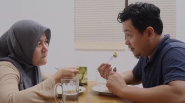 Asyalı çift, karı koca evde yemek yiyorlar.