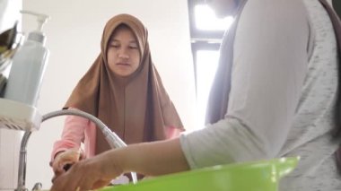 Endonezyalı Müslüman kadın kızıyla mutfakta yemek hazırlıyor, geleneksel otantik Asya yemekleri pişiriyor, doğal ışık.