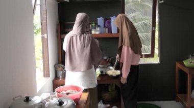 Endonezyalı Müslüman kadın kızıyla mutfakta yemek hazırlıyor, geleneksel otantik Asya yemekleri pişiriyor, doğal ışık.