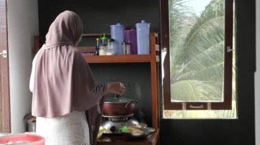 Endonezyalı Müslüman kadın kızıyla mutfakta yemek hazırlıyor, geleneksel otantik Asya yemekleri pişiriyor, doğal ışık.