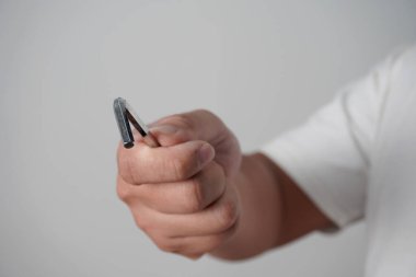 Gri arkaplanda altıgen allen anahtarı tutan bir erkek el.