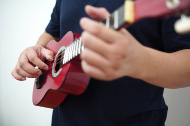 Asian man playing ukulele at home, anonymous person clipart