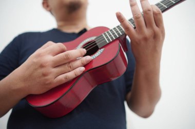 Evde ukulele çalan Asyalı bir adam, anonim biri.