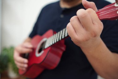 Evde ukulele çalan Asyalı bir adam, anonim biri.
