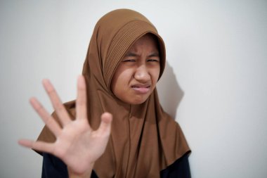 Genç Asyalı Müslüman kadın reddedilme jesti gösteriyor, endişeli bir ifade, öne çıkan el, öne doğru avuç içi dur işareti