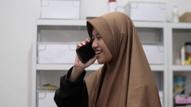 Genç Asyalı kadın telefonda konuşuyor, gülümsüyor.