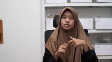 Genç Asyalı Müslüman kadın bir toplantıda röportaj yaparken ya da konuşurken bir şeyler anlatıyor ve anlatıyor.