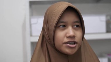 Genç Asyalı Müslüman kadın bir toplantıda röportaj yaparken ya da konuşurken bir şeyler anlatıyor ve anlatıyor.