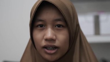 Genç Asyalı Müslüman kadın bir toplantıda röportaj yaparken ya da konuşurken bir şeyler anlatıyor ve anlatıyor.