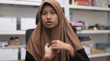 Genç Asyalı Müslüman kadın bir toplantıda röportaj yaparken ya da konuşurken bir şeyler anlatıyor ve anlatıyor.