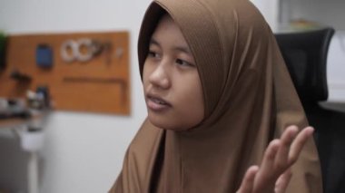 Genç Asyalı Müslüman kadın bir toplantıda röportaj yaparken ya da konuşurken bir şeyler anlatıyor ve anlatıyor.