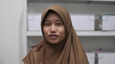 Genç Asyalı Müslüman kadın bir toplantıda röportaj yaparken ya da konuşurken bir şeyler anlatıyor ve anlatıyor.