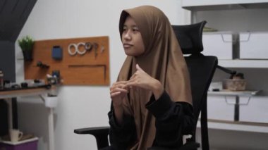 Genç Asyalı Müslüman kadın bir toplantıda röportaj yaparken ya da konuşurken bir şeyler anlatıyor ve anlatıyor.