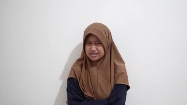 Genç Asyalı Müslüman kadın, tiksindirici bir ifadeyle, reddedilme jestleriyle ve rahatsız edici duygularla bakıyor.