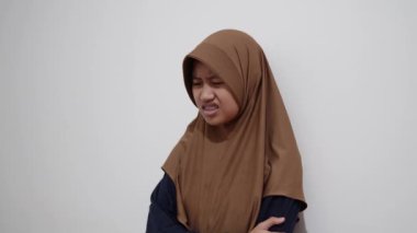 Genç Asyalı Müslüman kadın, tiksindirici bir ifadeyle, reddedilme jestleriyle ve rahatsız edici duygularla bakıyor.